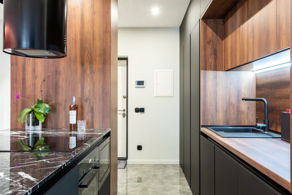 Modern kitchen with hob built in table with flower and bottle of liquor against tap in house